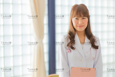 病院内に立つ若い女性医師の画像