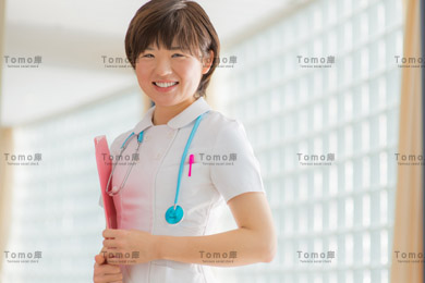 病院内に立つ笑顔の女性看護師（ナース）の画像