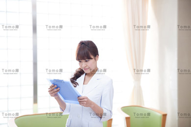 病院内で書類を読む若い女性医師の画像