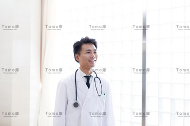 病院内に立つ笑顔の男性医師の画像