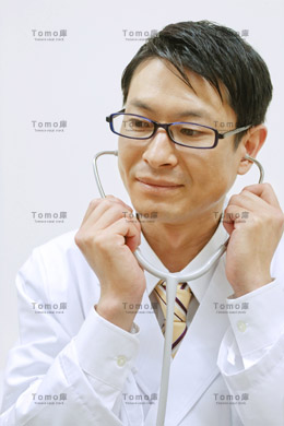 聴診器に手を当てる眼鏡をかけた男性医師の画像