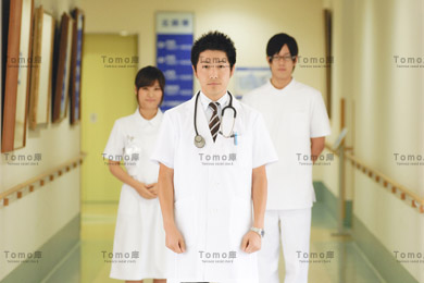 病院内に立つ若い男性医師と医療スタッフの画像