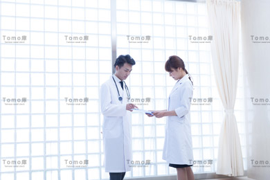 病院内に立つ男性医師と女性医師の画像