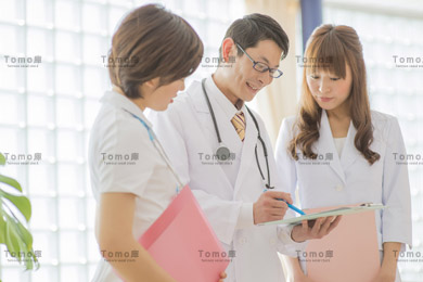 病院内で書類を見る男性医師・女性医師と女性看護師（ナース）の画像