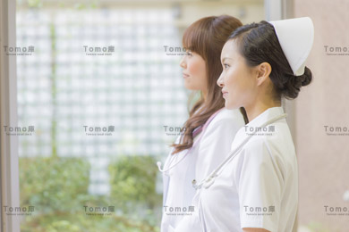 病院内から外を見る女性医師と女性看護師（ナース）の画像
