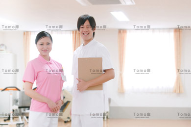 リハビリ室に立つ女性理学療法士と男性看護師の画像