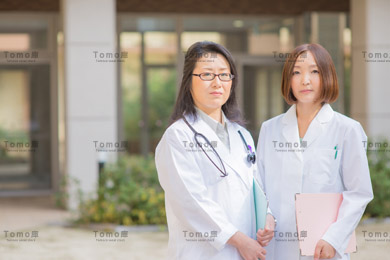 病院の中庭に立つ女性医師2名の画像