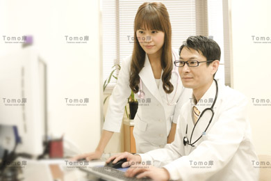 診察室でパソコンを触る男性医師と女性医師の画像