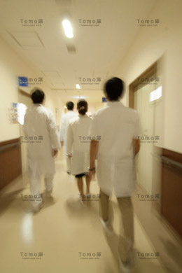 病院の廊下を急いで移動する医師と看護師・後姿