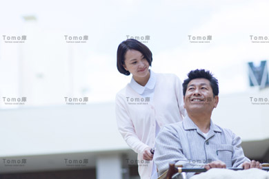 車椅子に座った笑顔の男性患者と女性看護師の画像