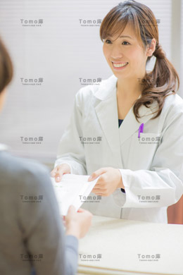 薬の受け渡しをする笑顔の女性薬剤師の画像