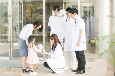 退院する女の子の患者を見送る医療スタッフたちの画像