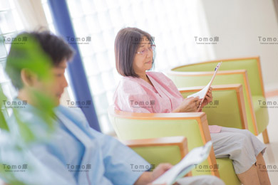 検査着で病院の椅子に座る男性・女性患者の画像・健康診断/検査
