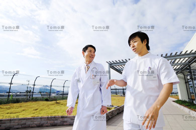 病院の屋上を歩く男性医師2名の画像